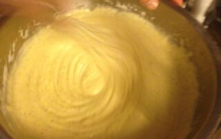 stalenkom waarin met een garde mayonaise wordt geklopt